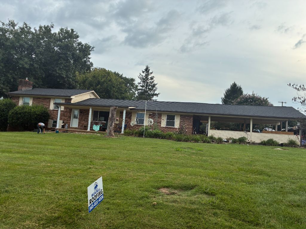 Brick ranch home with a newly completed dark shingle roof replacement