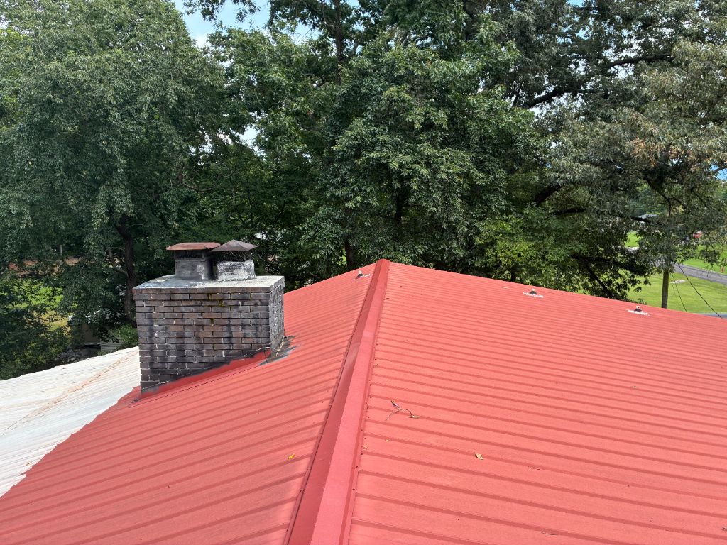 Before: close-up of an old red metal roof panel around the chimney