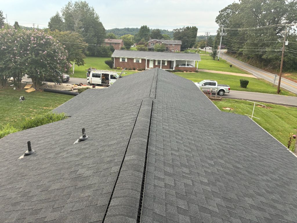 Aerial view of a completed dark architectural shingle roof from the ridge