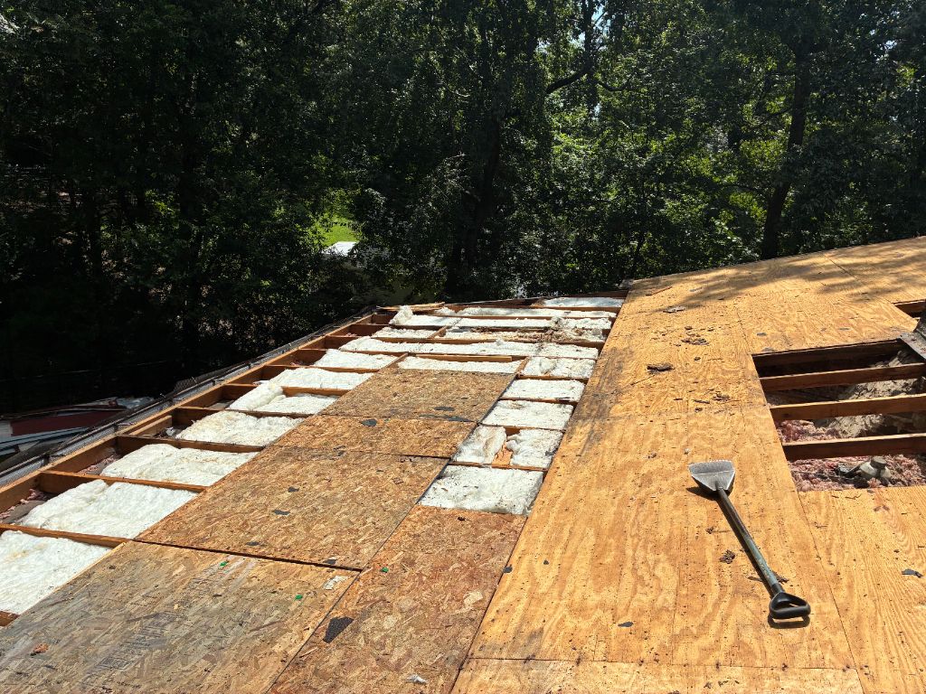 Close-up of exposed plywood roof decking and insulation during a tear-off