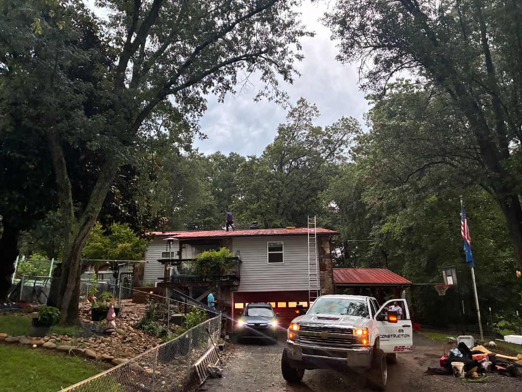 Split-level home mid roof tear-off with old red metal panels being removed