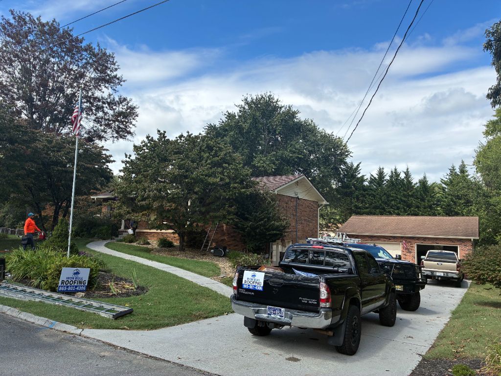 Completed Iron Bull Roofing job with trucks and yard sign, site cleaned up
